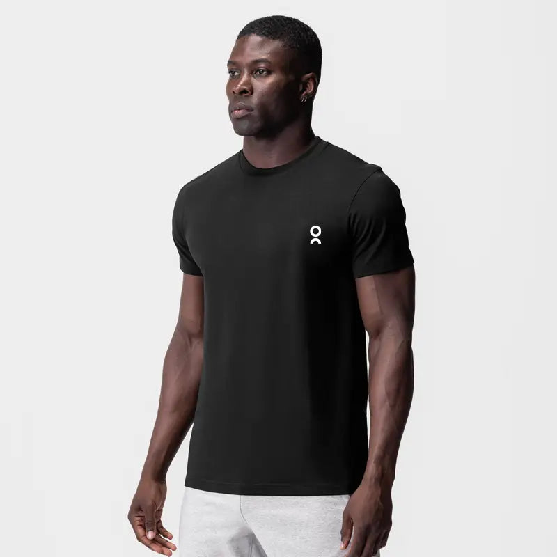 Camiseta deportiva de verano unisex negra con mangas cortas, cuello redondo, y logotipo pequeño blanco en el lado izquierdo del pecho.