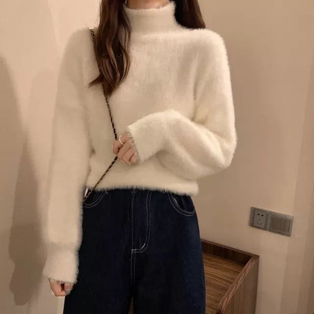 Cream-colored fluffy turtleneck sweater with long sleeves made of warm knit fabric for women winter wear.