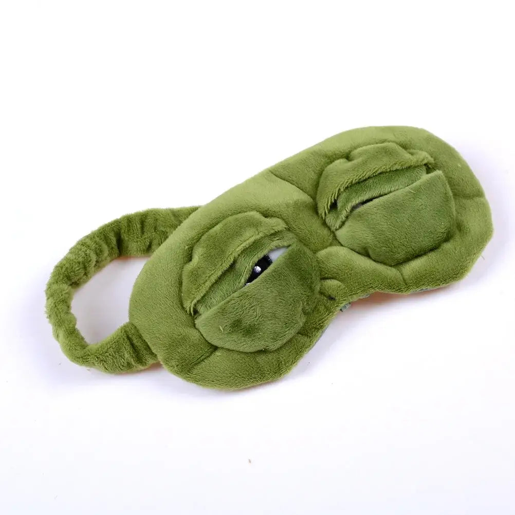 Máscara de dormir de rana verde de felpa con ojos bordados, elaborada con un tejido suave, presentada como producto terminado.