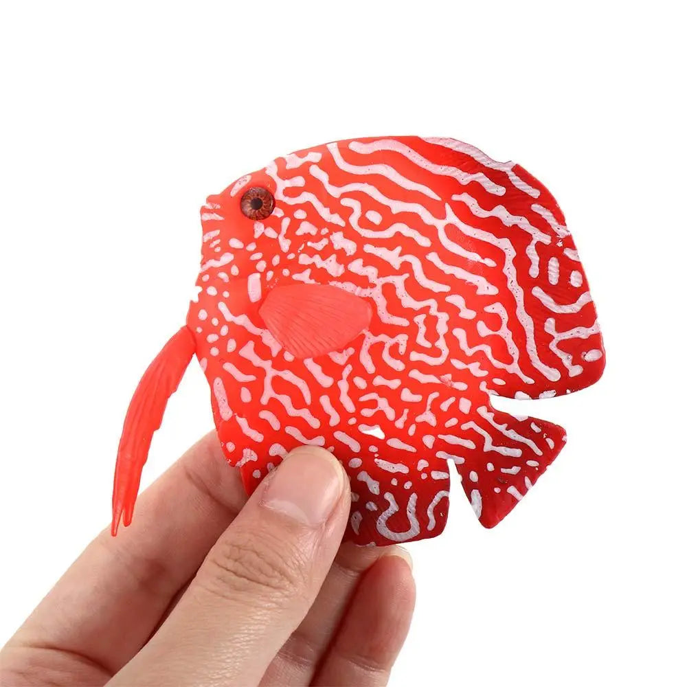 Eine kräftige rote künstliche Silikon-Aquarienzierde in Form eines Diskusfischs mit kunstvollen weißen wellenartigen Mustern und einem kleinen schwarzen Auge.