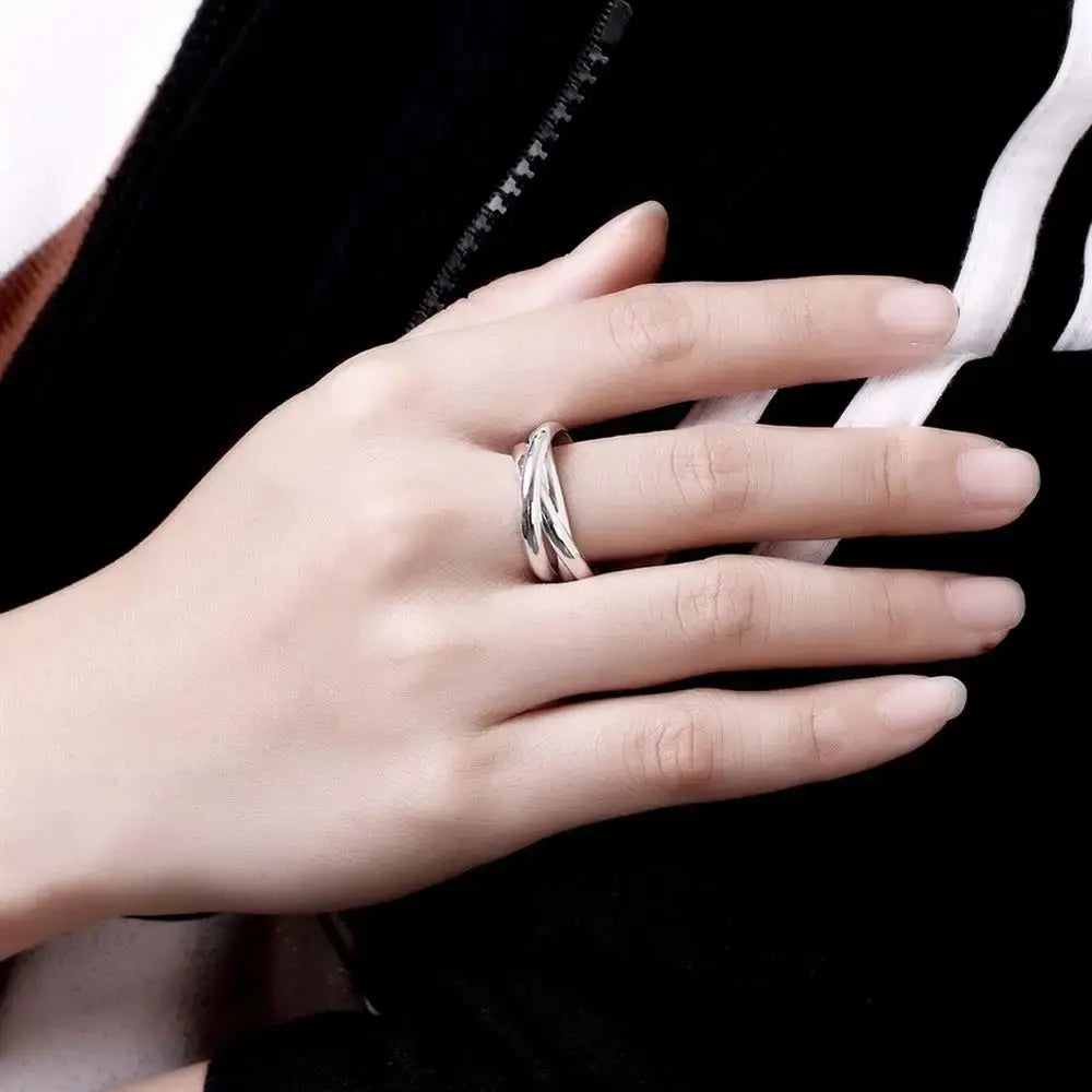 A sleek sterling silver ring for women with a simple three circles twisted interlocking band design worn on a finger.