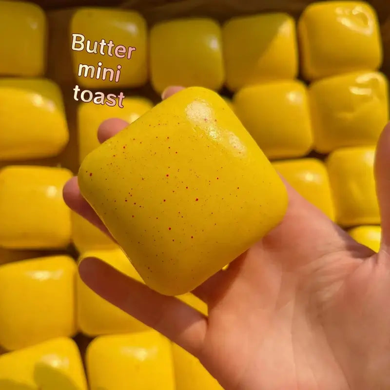 a vibrant yellow slow rising squishy mini toast with a glossy finish and tiny red speckles designed as a fidget toy