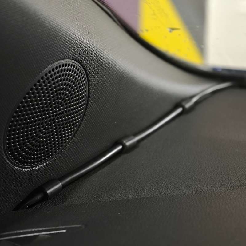 grille d’enceinte de voiture noire texturée avec un motif de perforations circulaires et un câble noir assorti, fixé à l’aide de pinces de câble pour tableau de bord de voiture, avec organisateurs de câbles à emboîtement s’emboîtant l’un dans l’autre