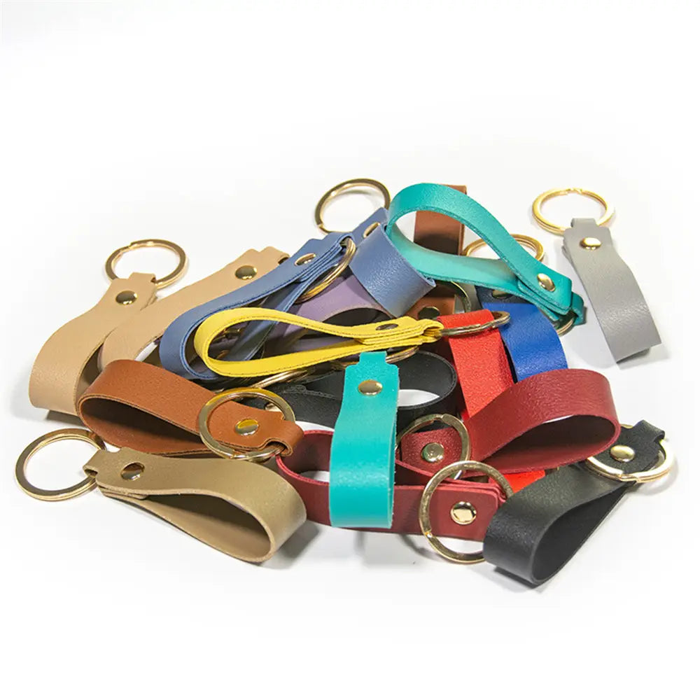 A collection of colorful pu leather keychains in tan blue yellow red and black featuring gold toned metal keyrings for fashionable use.