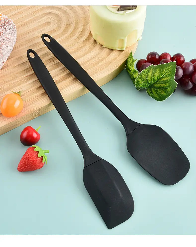 Black silicone kitchenware set featuring black silicone spatulas with smooth non-slip handles and slightly curved blades for baking and cooking.