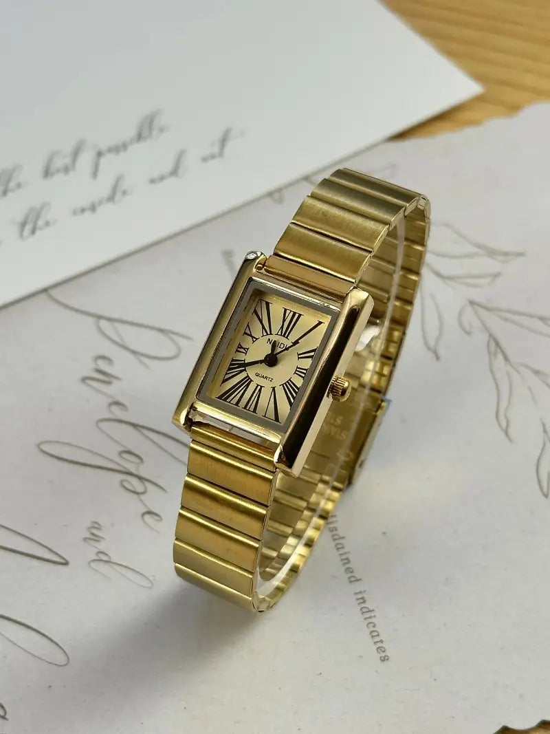 Vintage gold rectangular quartz watch for women with a gold-toned linked metal band and a classic roman numeral dial.