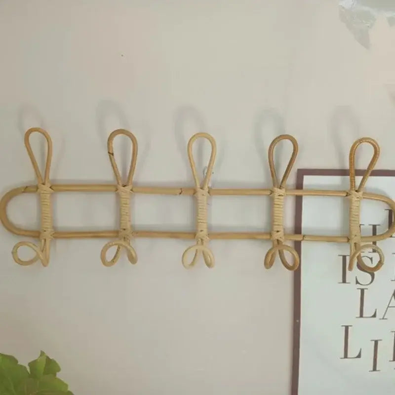 Natürlicher Rattan-Kinder-Wandhaken zur Aufbewahrung von Kleidung mit fünf geschwungenen, an der Wand montierten Haken in hellbrauner Farbe.