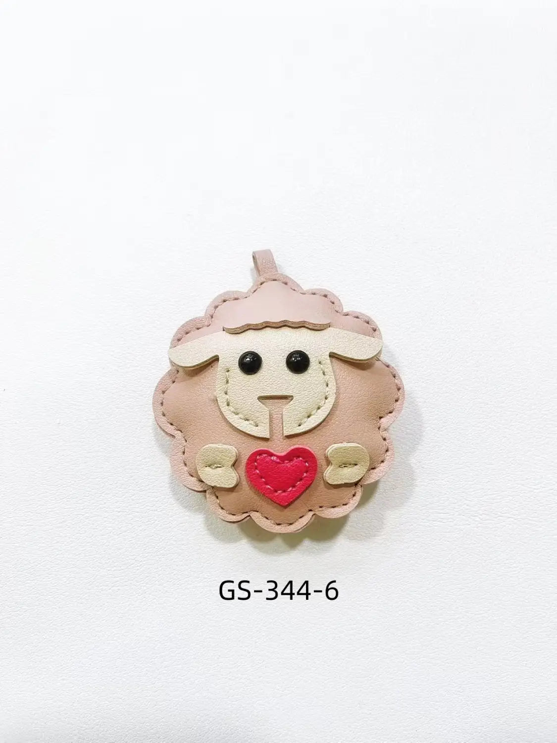 A soft pink lamb-shaped leather sheep keychain with a red heart stitched on its chest designed as a cute animal bag charm.
