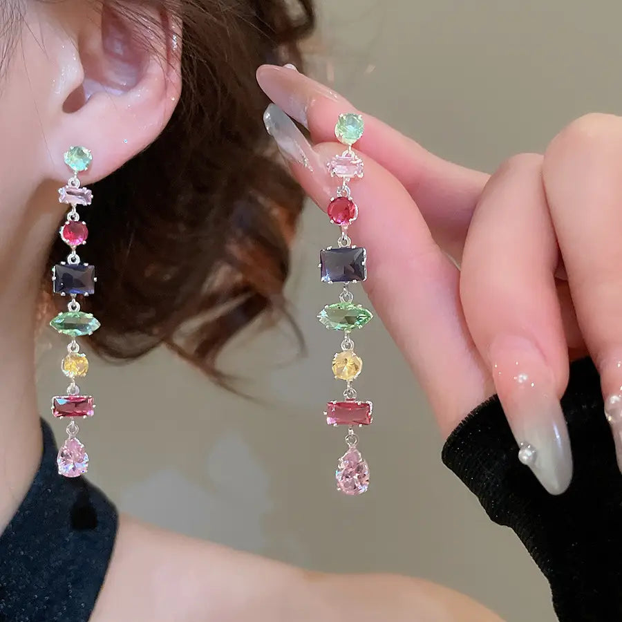 A pair of dangling earrings with a cascade of colorful faceted zircon crystals in various shapes and sizes set on silver-toned metal.
