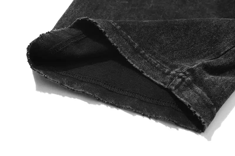 Tela de mezclilla (denim) negra con dobladillo deshilachado y costuras visibles, presente en la camiseta extragrande vintage lavada y desteñida con gráfico de anime gótico.