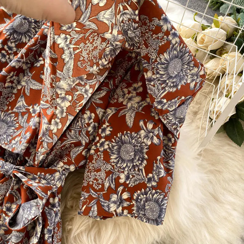 Blusa color óxido con un patrón detallado floral negro y blanco, con mangas con volante y cintura atada, estilizada como parte de un enterizo de pierna ancha floral con escote tipo bardot.