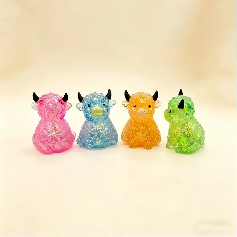 Four translucent glittery highland cow sensory fidget toys in pink blue orange and green designed for stress relief.