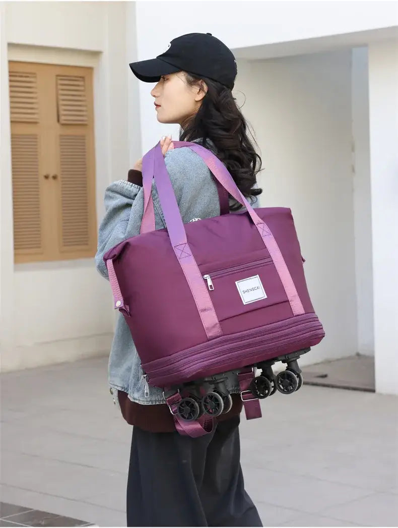 Un sac duffel roulant violet à grande capacité, avec des sangles roses et une étiquette blanche, conçu pour un usage de grand sac à dos et de voyage.