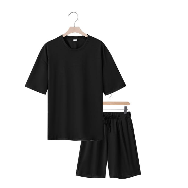Conjunto veraniego de dos piezas para hombre, camiseta casual negra de algodón de manga corta y conjunto de pantalones cortos a juego, colgados en perchas de madera.