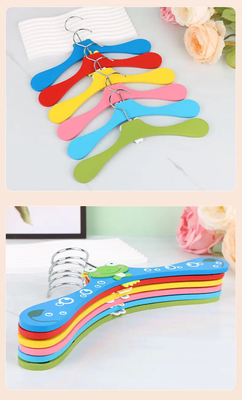 Set aus farbenfrohen Cartoon-Holz-Baby-Kleiderbügeln mit verspieltem Froschdesign und Metallhaken.