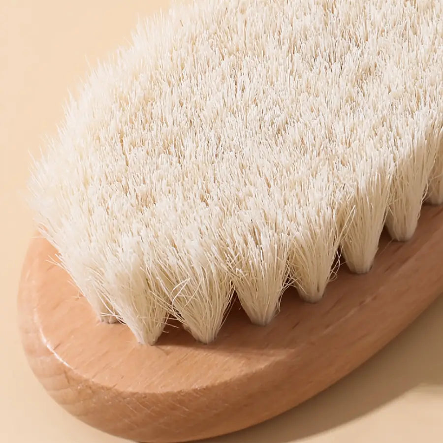 A natural wood-handled baby body brush with dense off-white bristles arranged in a zigzag pattern from the baby wooden grooming set and healthcare kit.