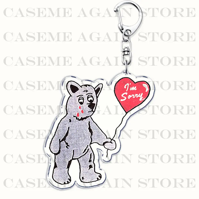 Silver acrylic keychain featuring a cartoon bear with blood-like red marks on its face holding a red heart-shaped balloon reading im sorry from the Gracie Abrams anime fan gift collection.