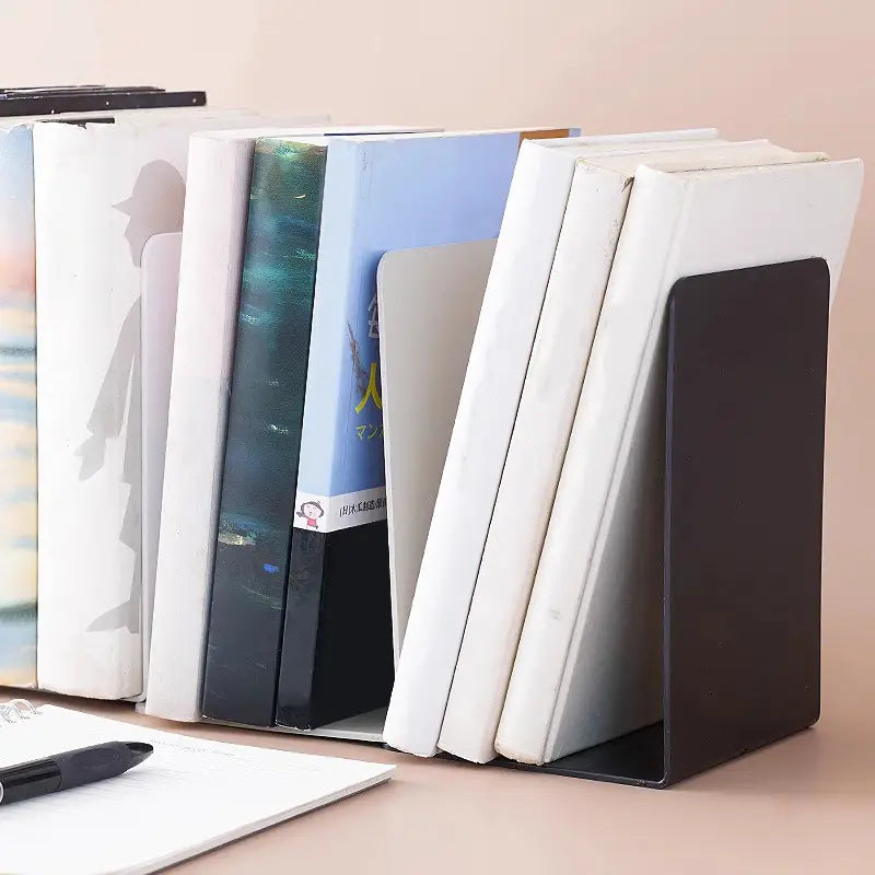 Black metal L shaped minimalist bookend holding a stack of books upright on a desktop.