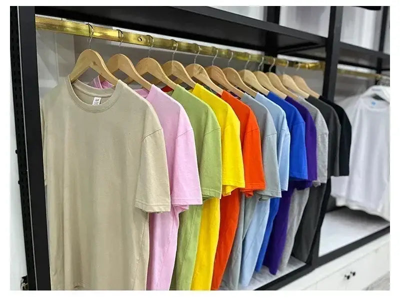 Une rangée de t-shirts vintage à motif de voiture de muscle en coton uni et coloré, suspendus à des cintres en bois.
