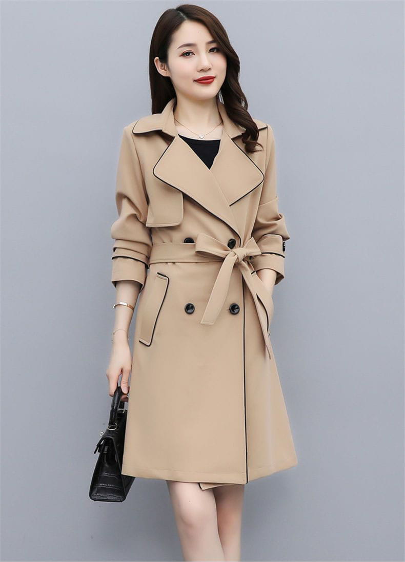Beige women double breasted trench coat with black trim and matching belt made from lightweight fabric for versatile outerwear.
