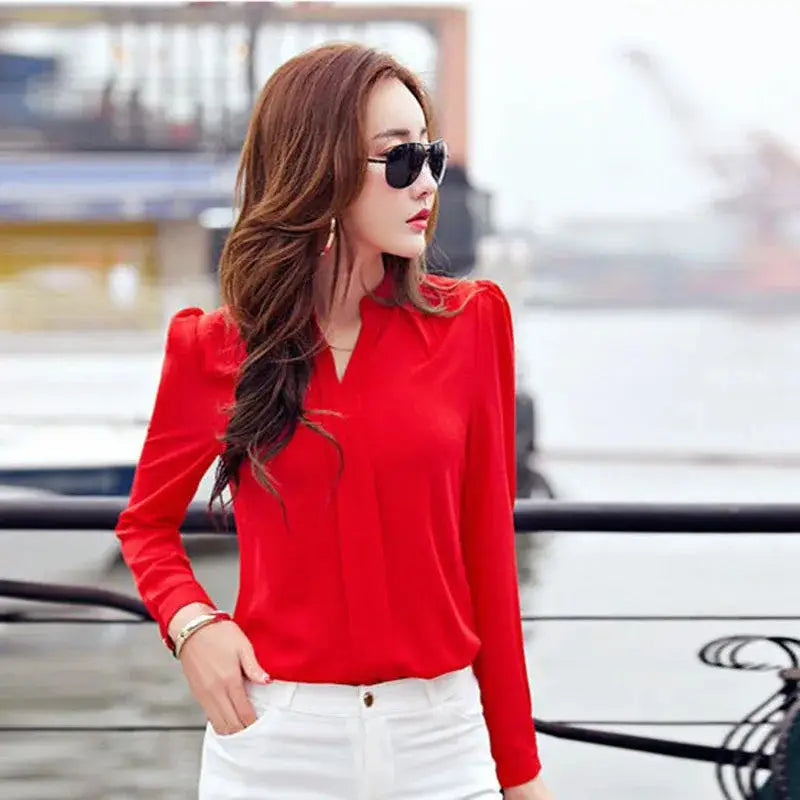 A vibrant red long sleeve office blouse for women with a v neckline and puffed shoulders made from lightweight fabric.