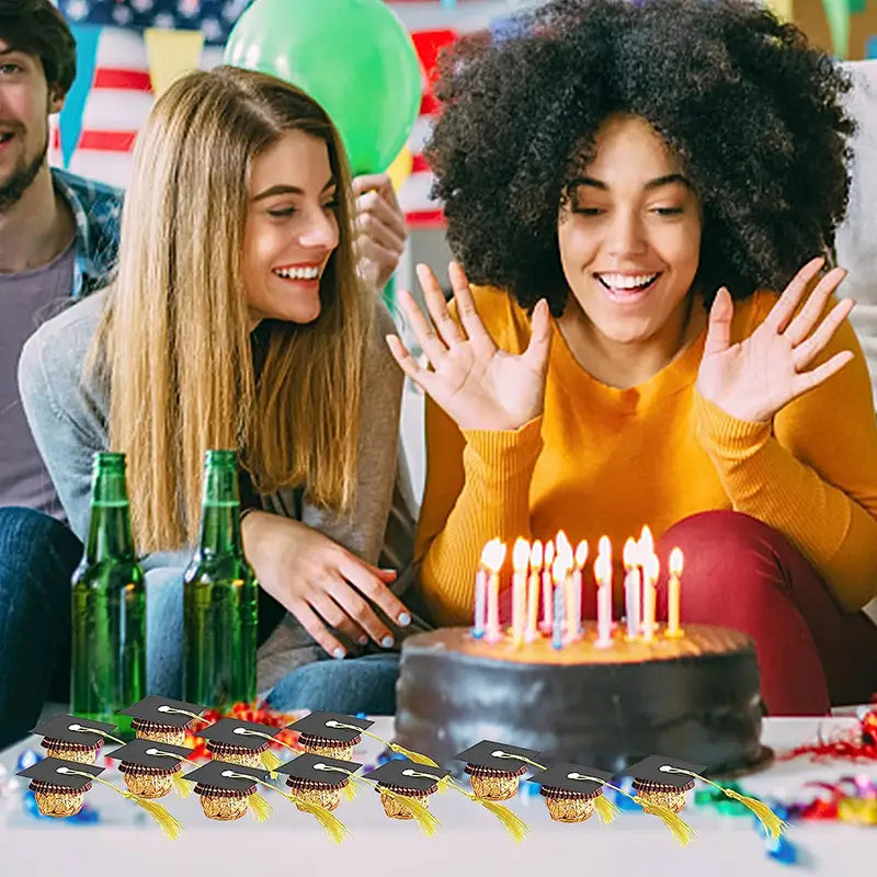Vasos para obsequios de fiesta con temática de birrete de graduación negro, con acentos de papel metalizado dorado y borlas amarillas para decoraciones de chocolate y caramelos de birrete de graduación 2025.