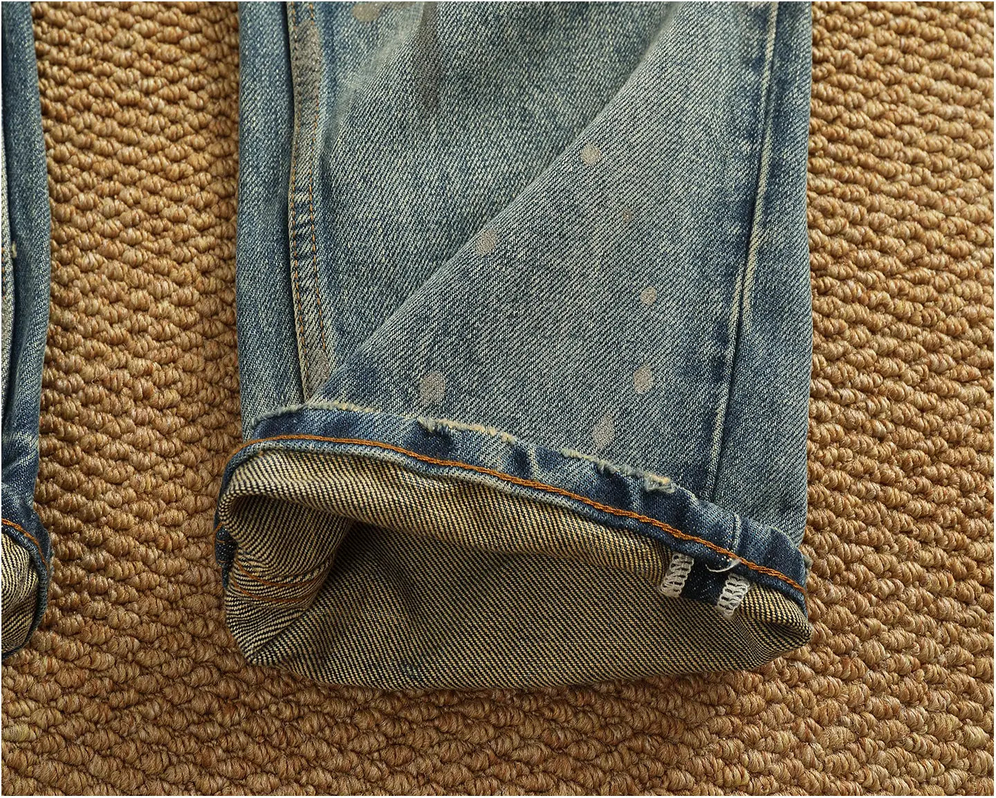Light-wash denim distressed patchwork jeans for men featuring a rolled cuff and subtle distressing on light denim material.