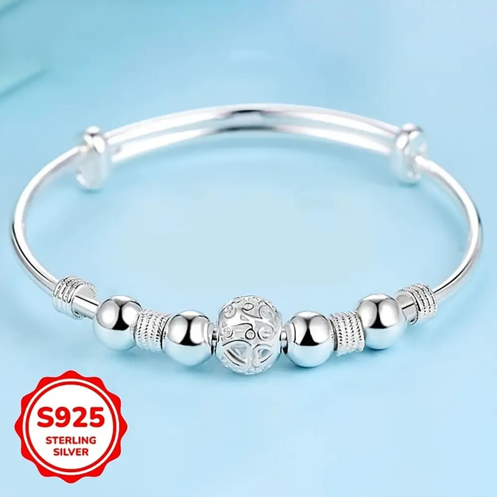Sterling silver beaded bangle bracelet for women featuring an exquisite central ornate bead with smooth spherical beads and textured cylindrical spacers, ideal as a party gift.