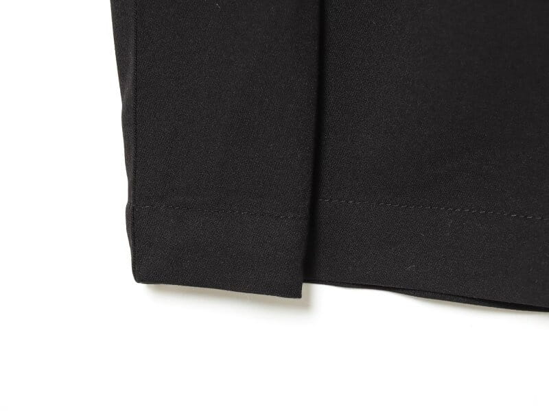 Pantalons noirs taille haute plissés à jambes évasées, avec un tissu mat lisse et un ourlet soigneusement cousu