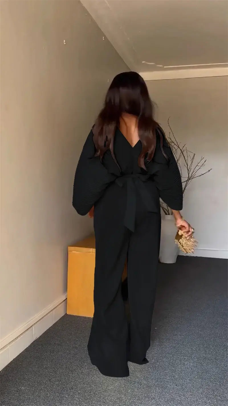 black wide-leg jumpsuit with tied waist and deep v-back shown from the back in a purple satin two-piece set wide leg pants product image.