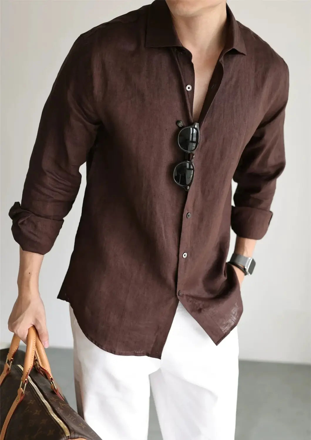 A dark brown long-sleeved cotton linen casual button down shirt with rolled cuffs and a collar for men.