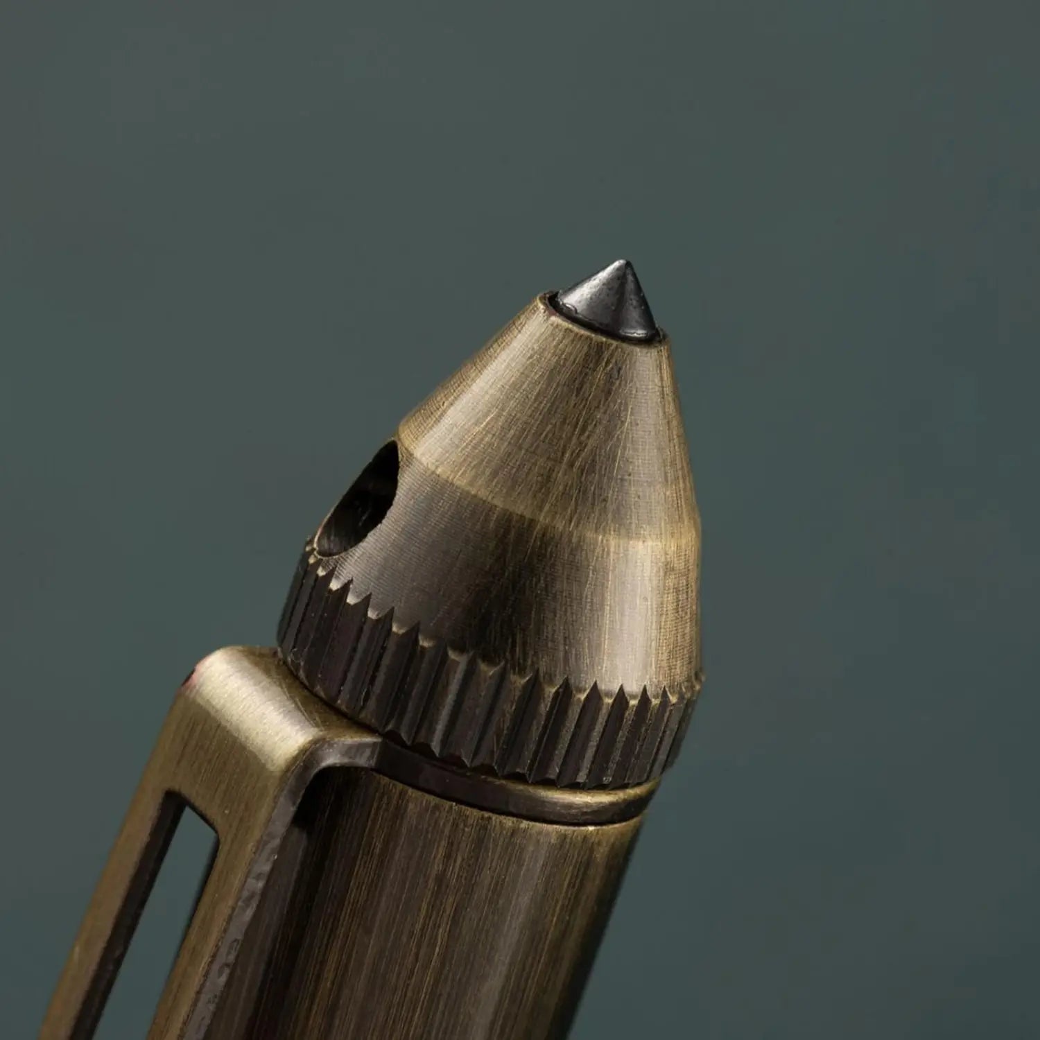 Un taille-crayon ancien en laiton, avec une finition brossée texturée et une pointe en métal noir, issu de la collection de stylos de voyage rétro en laiton pour hommes.