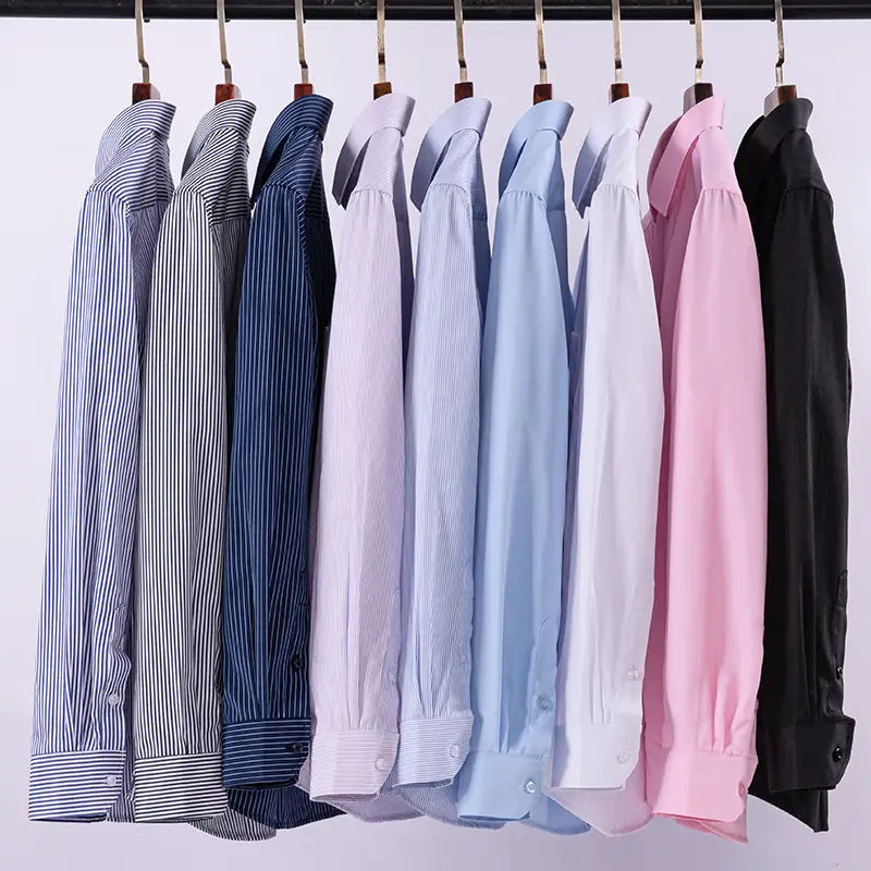 Eine Kollektion von Herren gestreiften Businesshemden mit langen Ärmeln mit verschiedenen unifarbenen und gestreiften Mustern in Farben von Navyblau bis Pink, ordentlich aufgehängt.