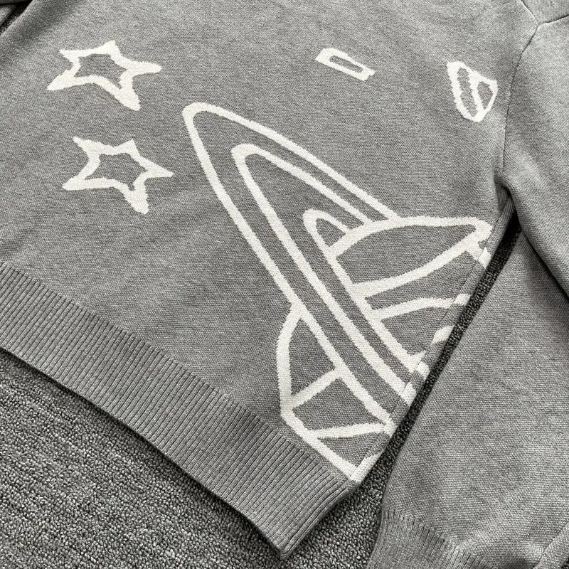 suéter de punto gris con diseño bordado en blanco de temática espacial que presenta un planeta y estrellas en un suéter de punto con bordados y gráfico