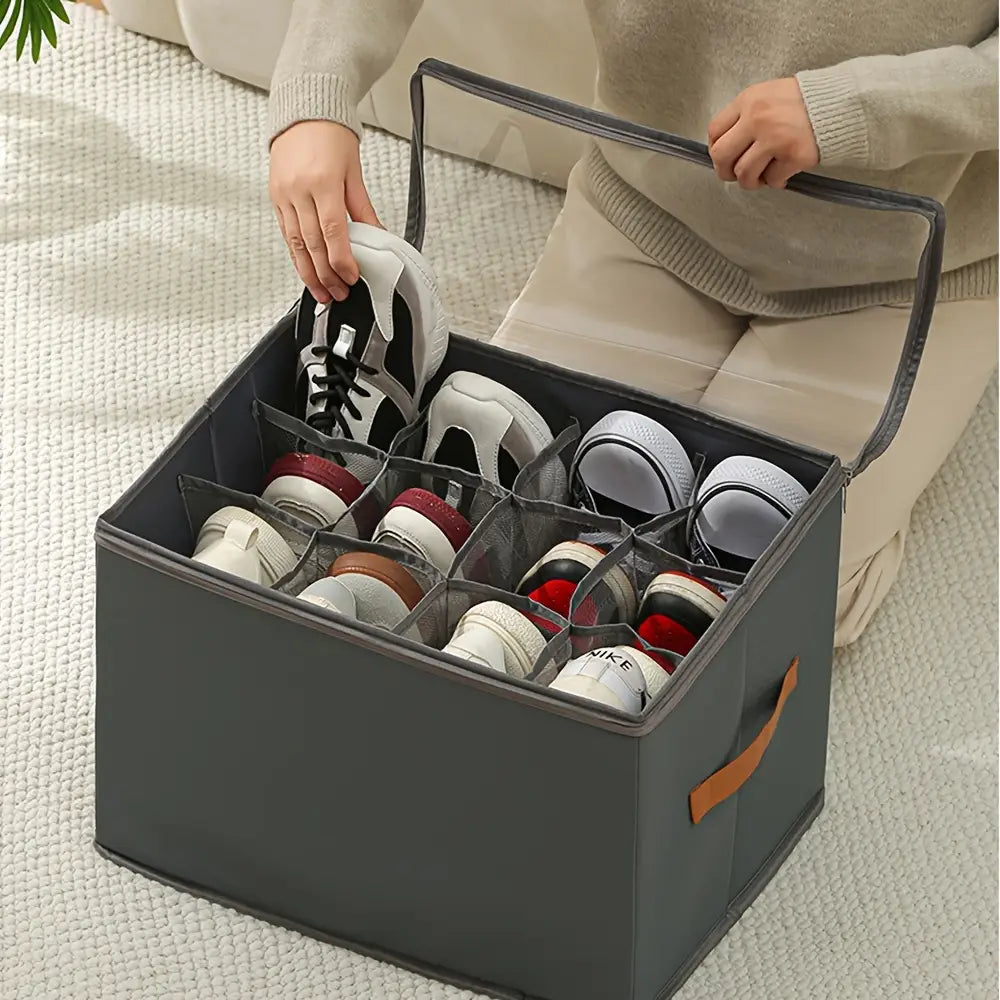 Organisateur de rangement pour chaussures en tissu gris avec design pliable en tissu d’oxford, compartiments transparents et poignée en cuir brun pour un rangement pratique des chaussures.