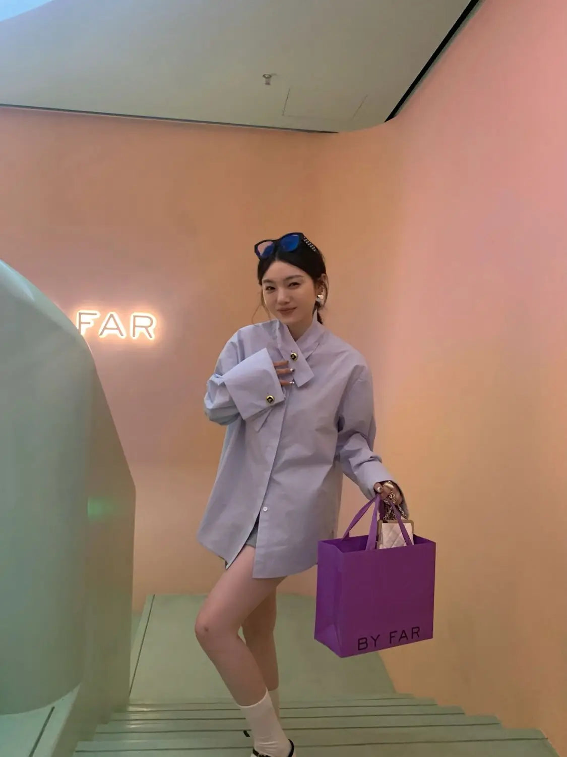 purple by far shopping bag displayed alongside a light blue oversized button up shirt highlighting casual style and relaxed fit