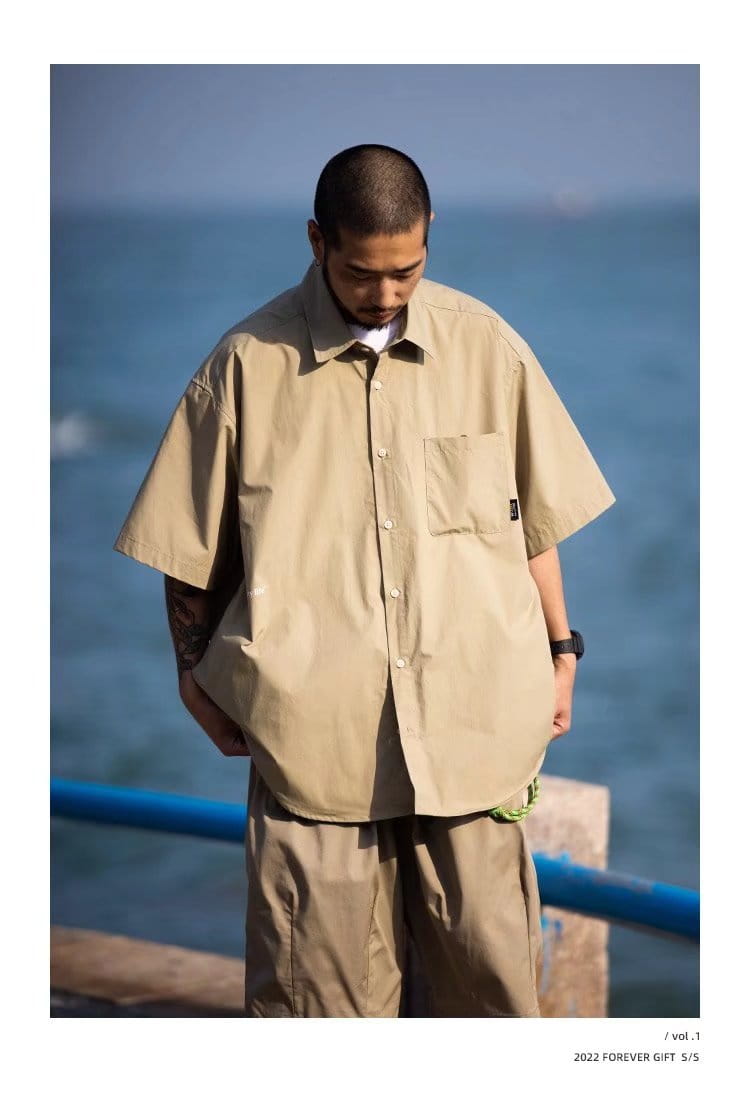 Beige mens casual short sleeve button up shirt with chest pocket and subtle branding on the flap.