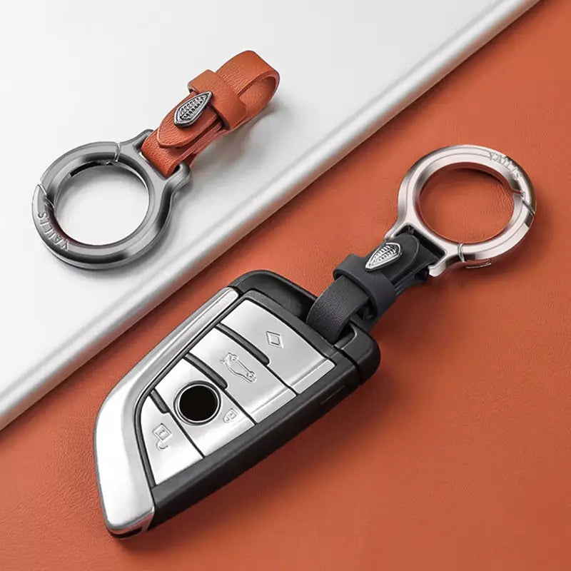 Leather car keychain with silver and black car key fob cover featuring a leather strap and metal ring with a leaf charm.