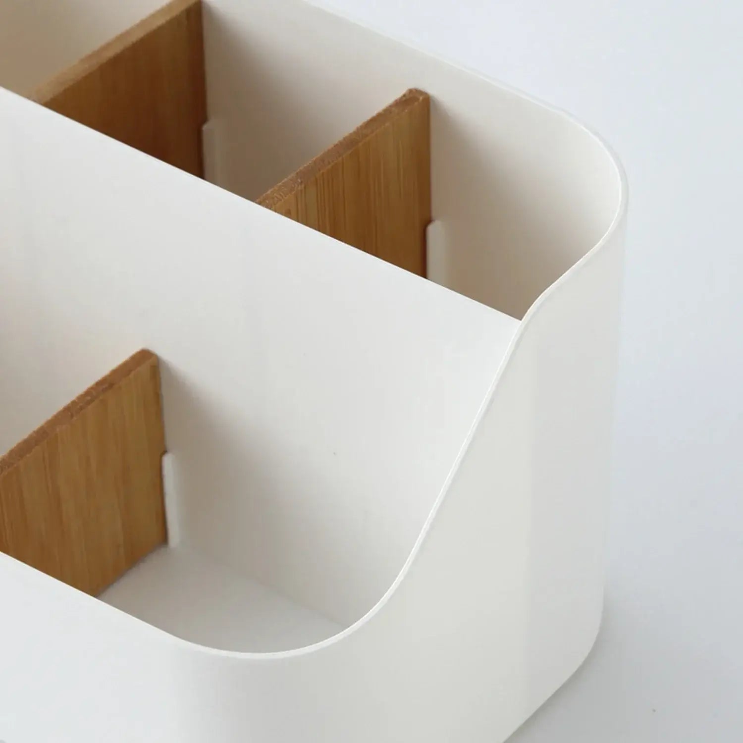 White plastic desk organizer with light wood-tone bamboo dividers designed as a makeup brush holder.