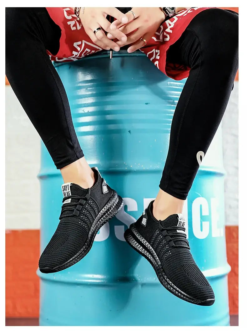 Herren-Atmungsaktive legere Strick-Sneaker aus schwarzem Mesh mit modernem, elegantem Design und dezenter Markenkennzeichnung an der Seite.