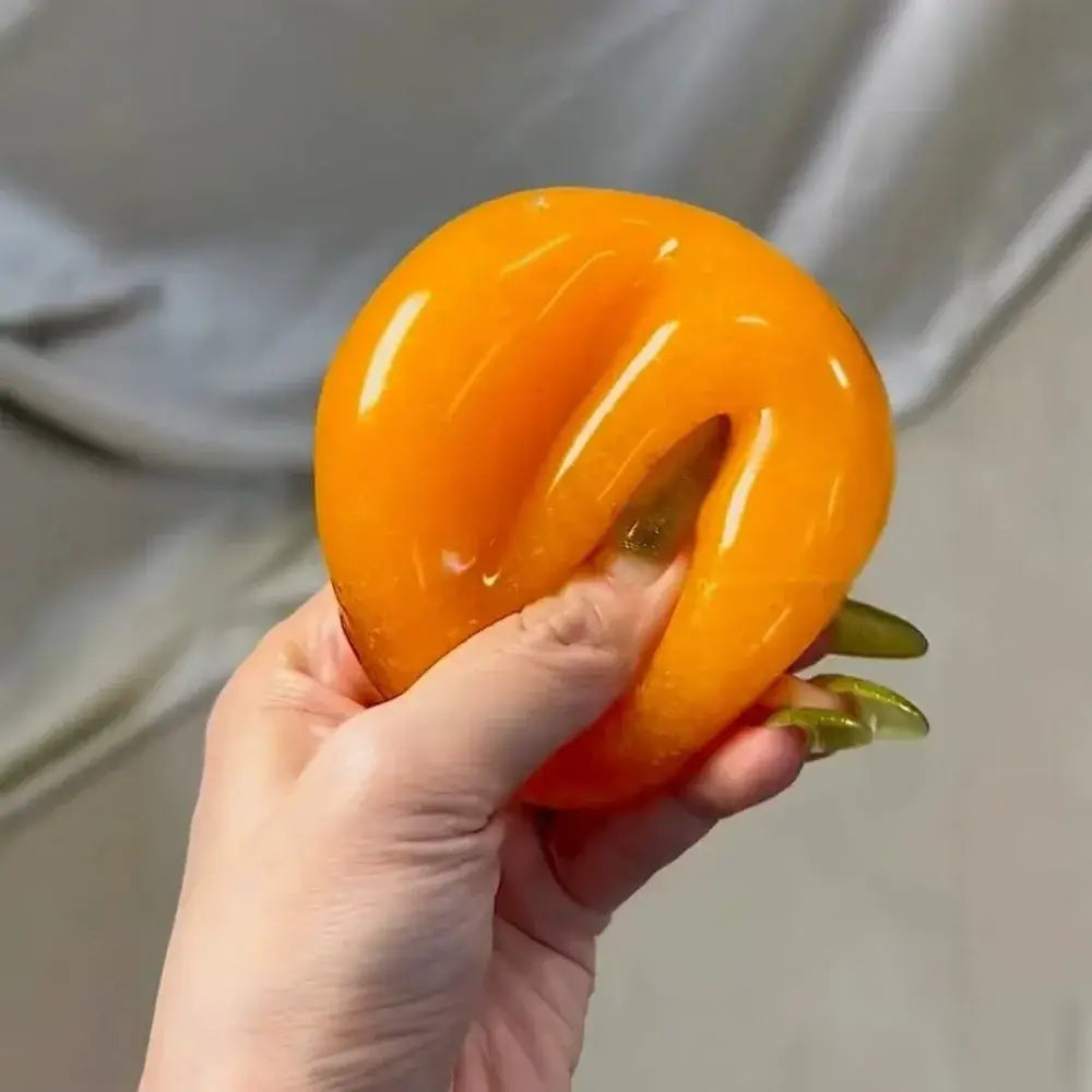 A vibrant orange slushy squishy stress relief toy with a glossy finish and a distinctive split design shown from the front.