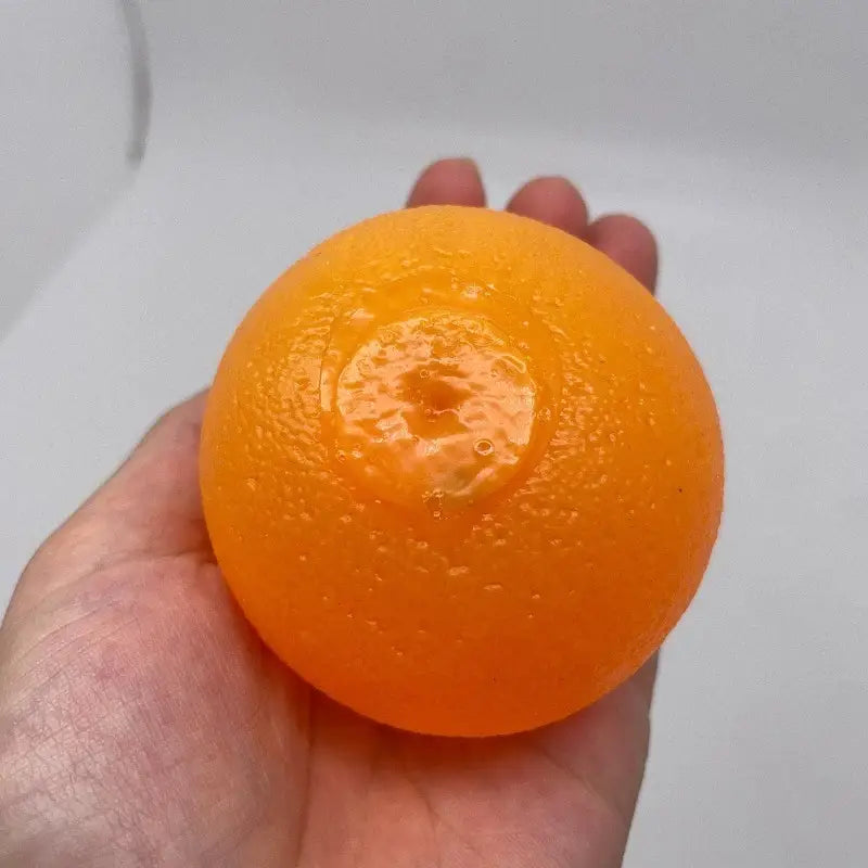 Un jouet sensoriel d’anti-stress en silicone orange, vibrant, brillant et texturé comme un véritable fruit d’agrumes.