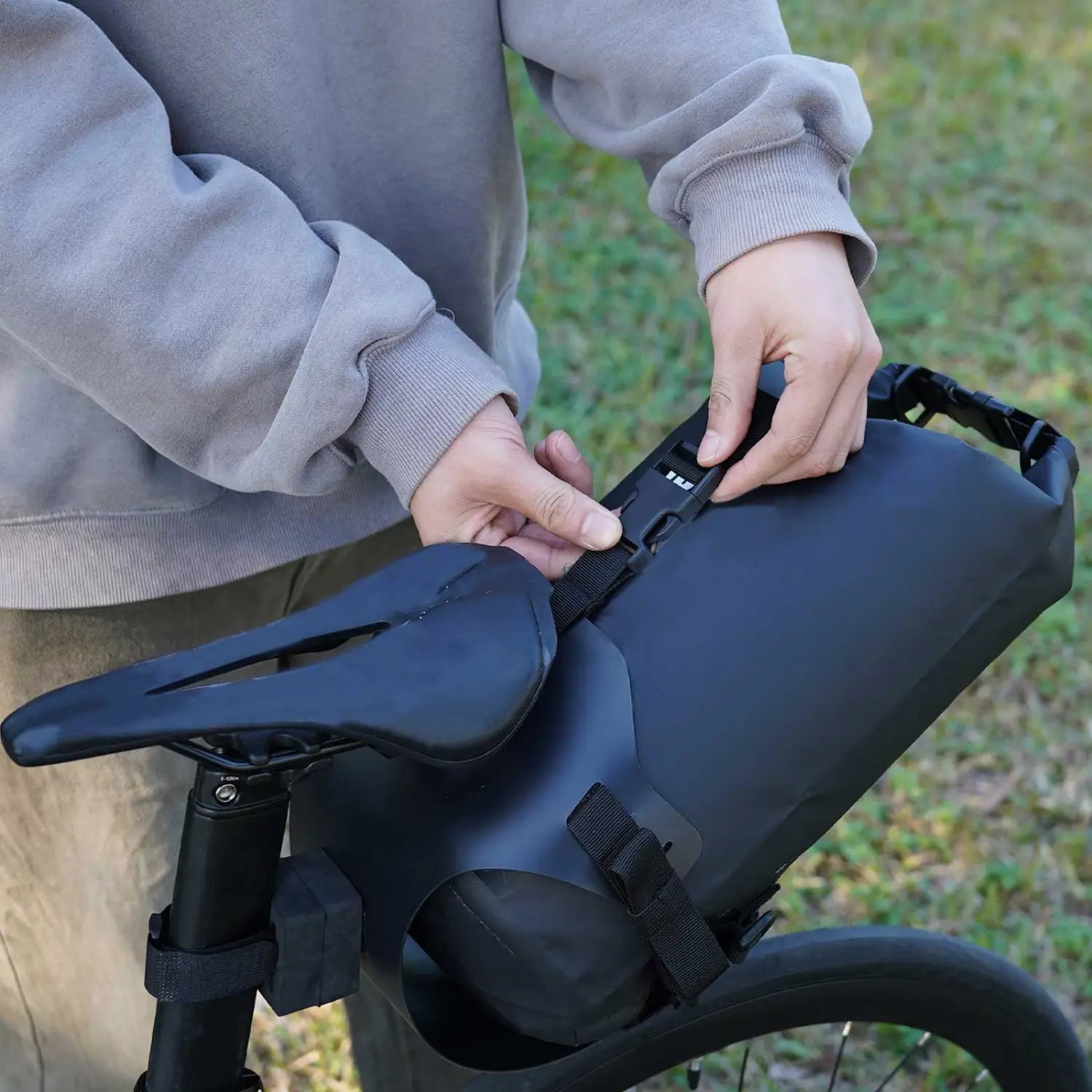 Black waterproof bike saddle bag stabilizer bracket carrier with adjustable straps and roll-top closure shown from the back side