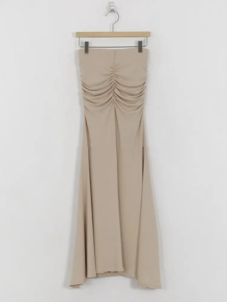 Beiges ärmelloses Maxikleid mit gerafftem Oberteil und fließendem Stoff, kombiniert mit einem rosa gerafften Meerjungfrauen-Midirock mit hoher Taille.