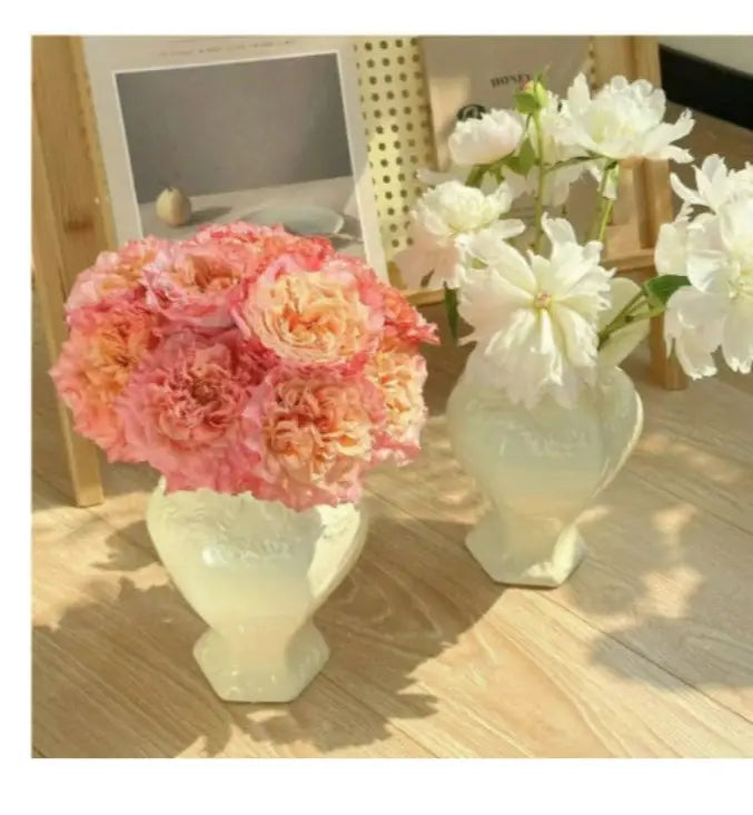 Jarrones de cerámica modernos franceses color crema con intrincados patrones en relieve; cada uno sostiene un ramo de flores para una decoración elegante del hogar.