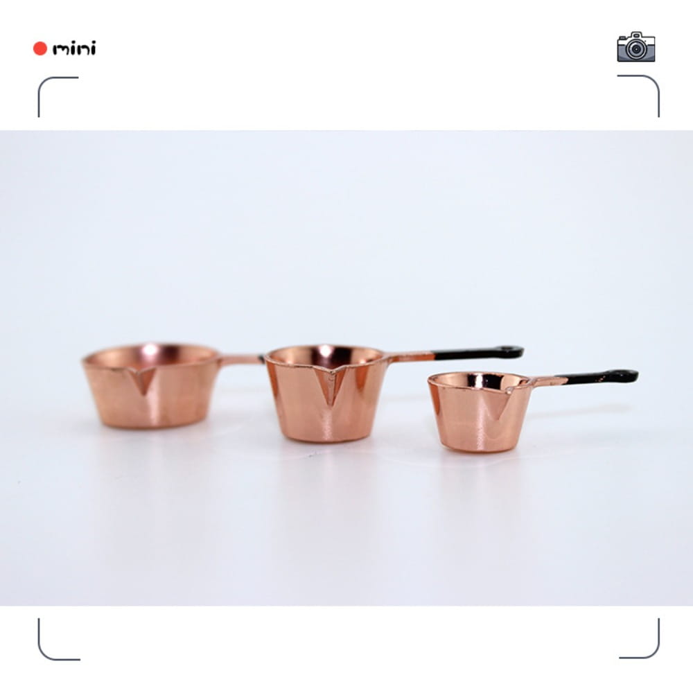 Ensemble de trois petites tasses à mesurer de cuisine miniature en cuivre pour maison de poupée, avec des poignées noires.