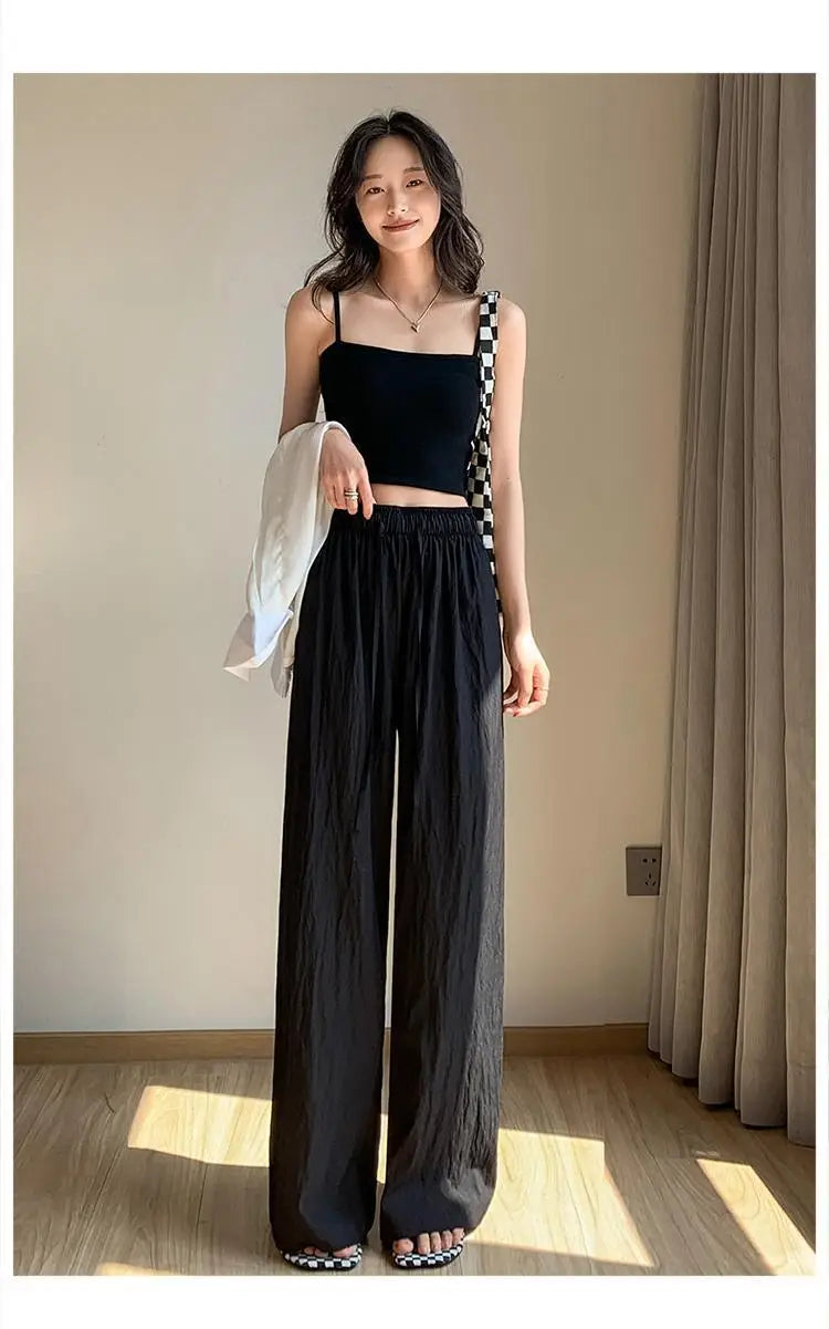 Schwarze weite Plissee-Hose für Damen mit entspannter, fließender Silhouette und dezenten vertikalen Falten, ideal für die Sommerzeit