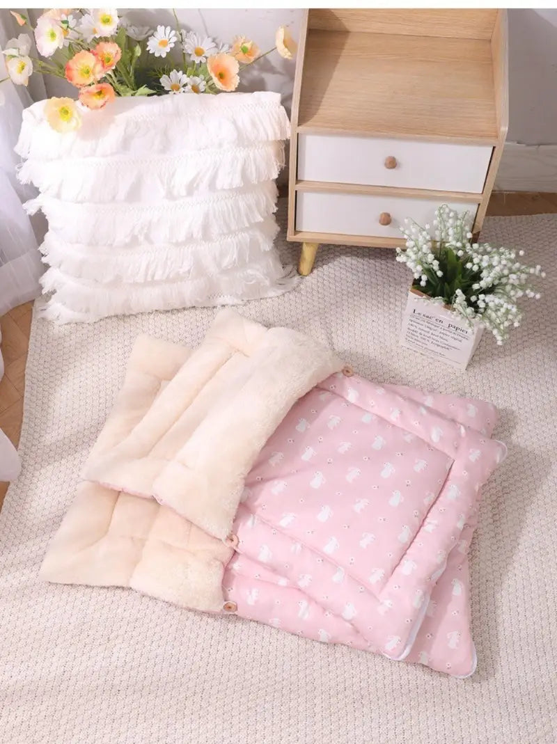 Cama acolchada para gato rosa con liebre durmiendo, bolsa de dormir con un diseño acolchado suave en rosa y crema, que presenta patrones de corazones blancos en el lado rosa