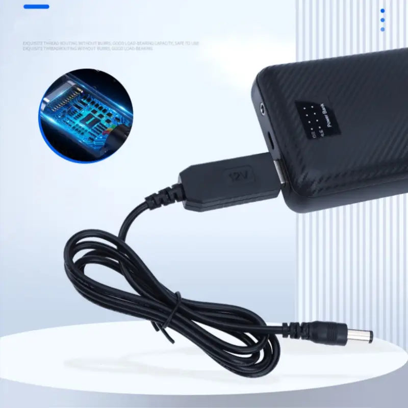 Black usb-a to barrel jack 5v to 21v usb boost charging cable connected to a black portable power bank with a carbon fiber texture.