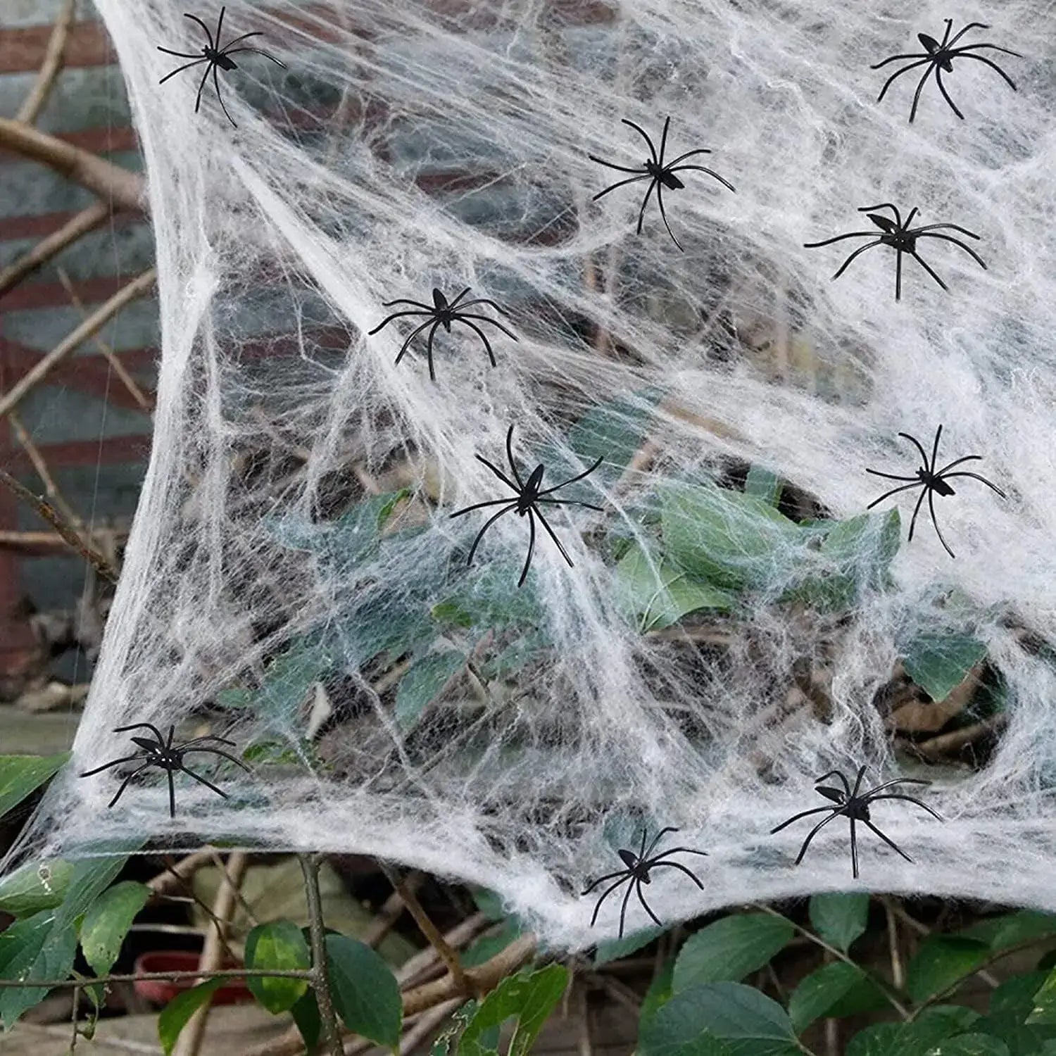 una decoración ornamental de telaraña blanca de máxima elasticidad con varias arañas de plástico negras dispersas sobre ella para decoraciones de fiesta de Halloween